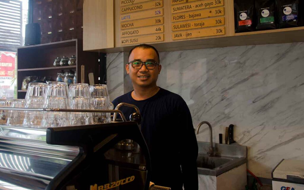 Bli Dika Meidika barista Iraga Coffee standing behind espresso machine. Photo: pourmorecoffee.com
